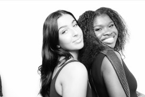 Three women glamorously posing for a photo in a black and white photo booth.