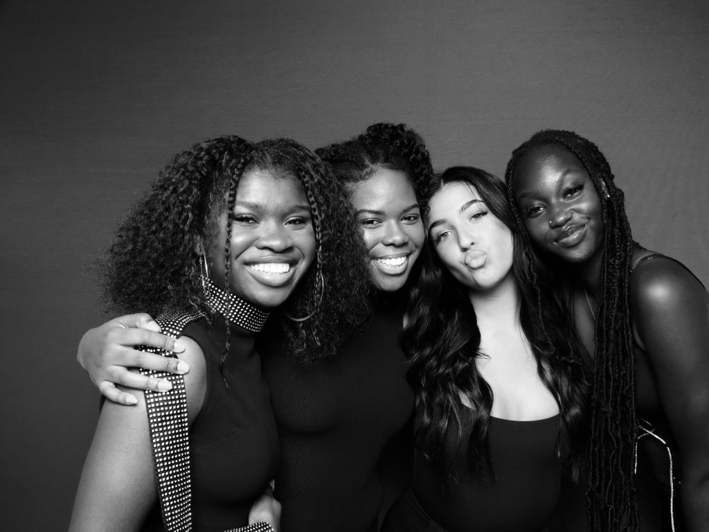 A black and white photo of a group of women posing for a glam photo booth shot. A black and white photo of a group of women posing for a glam photo booth shot.