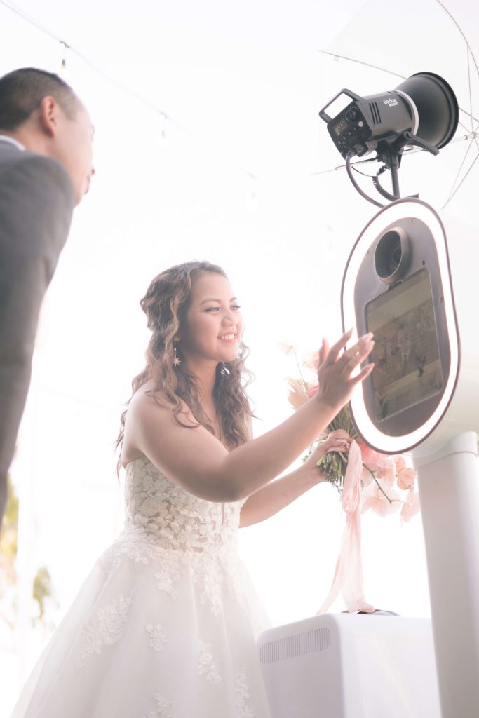 A bride and groom standing next to a wedding photo booth.