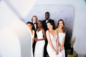 A group of people posing for a wedding photo in front of a mirror.