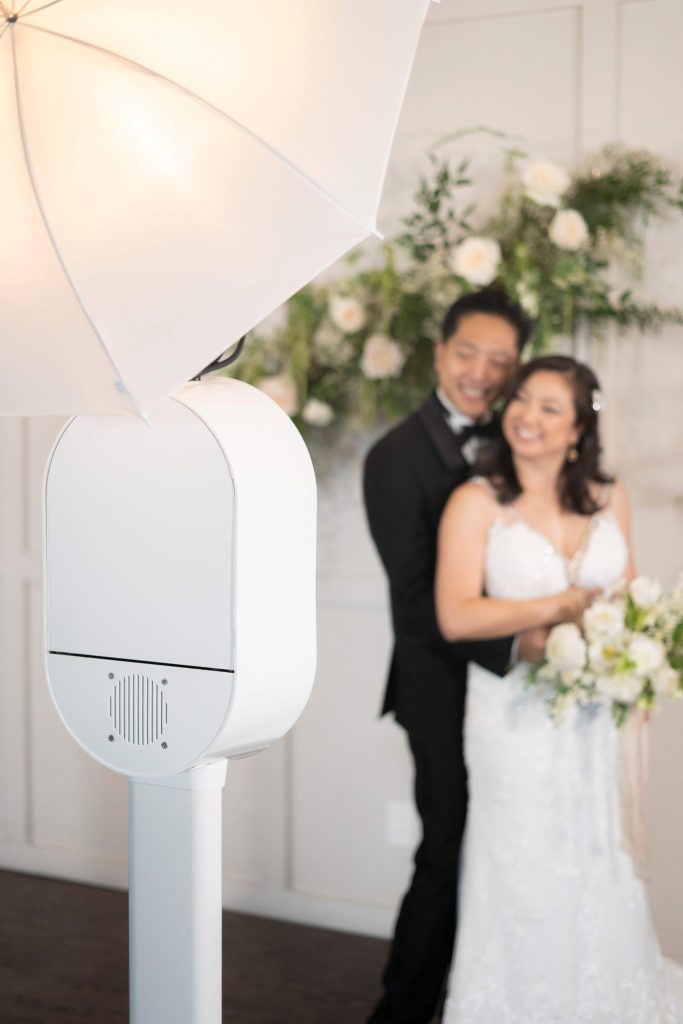 A bride and groom posing for a wedding photo in front of an photo booth.